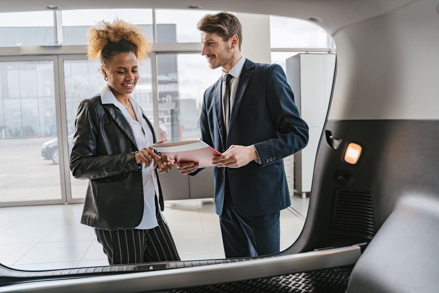 Twee mensen bekijken papieren bij een auto